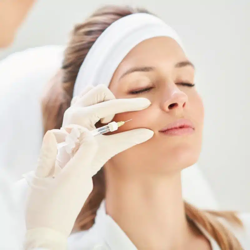 Un professionnel effectue une injection de toxine botulique sur le visage d'une femme.