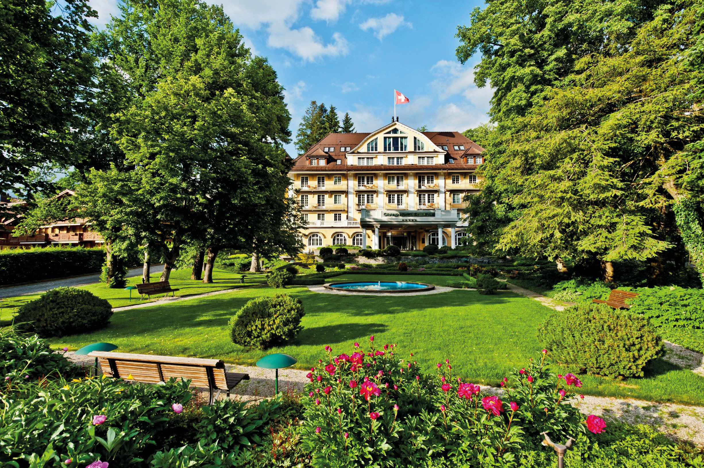 Vue du Grand Bellevue Spa à Gstaad, où se trouve la deuxième clinique esthétique de Dr Djoon, avec un grand jardin en premier plan.